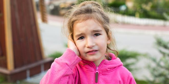 a young girl in pain from a childhood ear infection